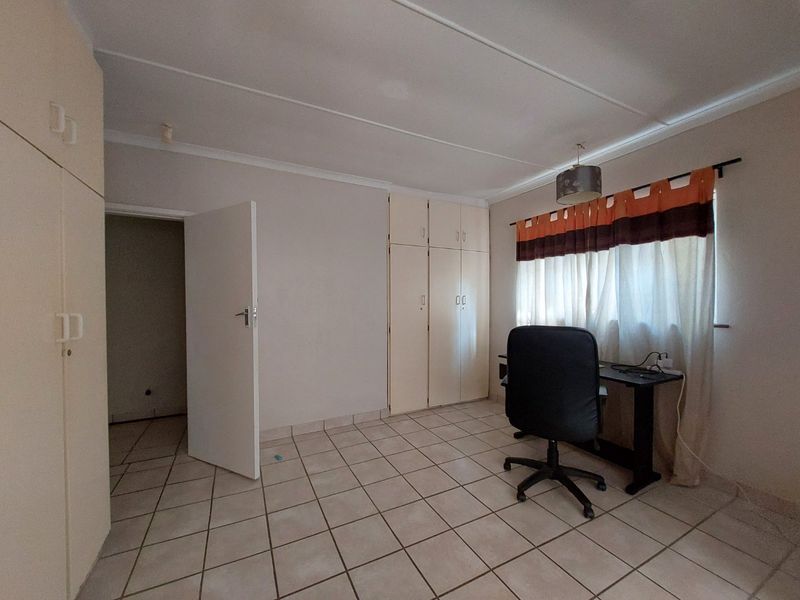 A functional bedroom featuring tiled flooring and built-in cupboards, offering a neutral space ready for personalization.