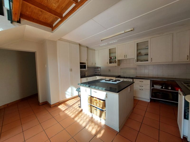 A functional kitchen featuring a central island, granite countertops, built-in cabinetry, and tiled flooring, offering a practical layout with potential for modern updates.