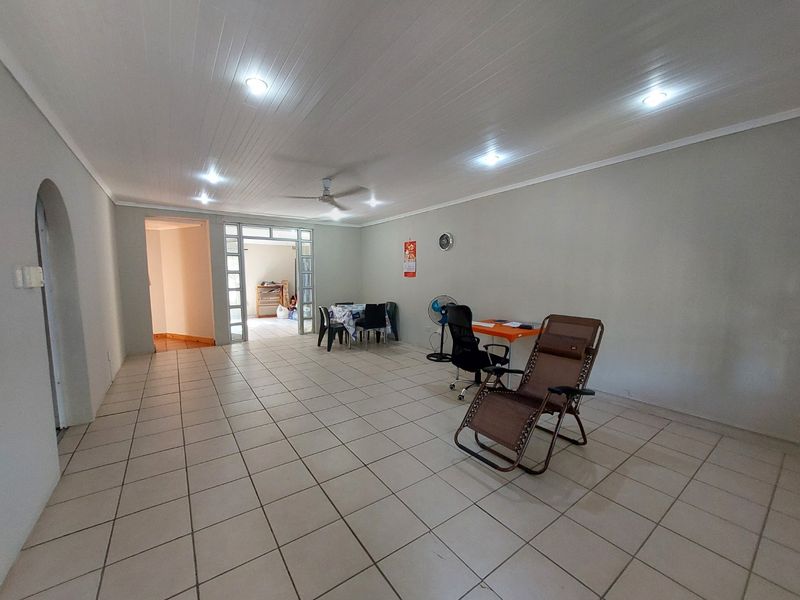 Spacious open-plan living area featuring tiled flooring, recessed ceiling lighting, and a ceiling fan, providing a versatile space for relaxation or dining.