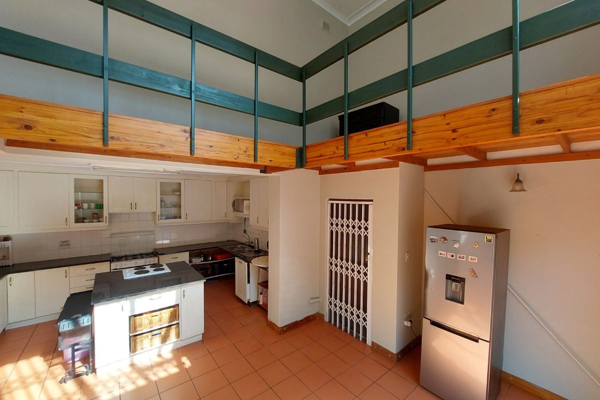 Spacious kitchen featuring a central island, ample cabinetry, and a mezzanine level overlooking the cooking area with tiled flooring throughout.