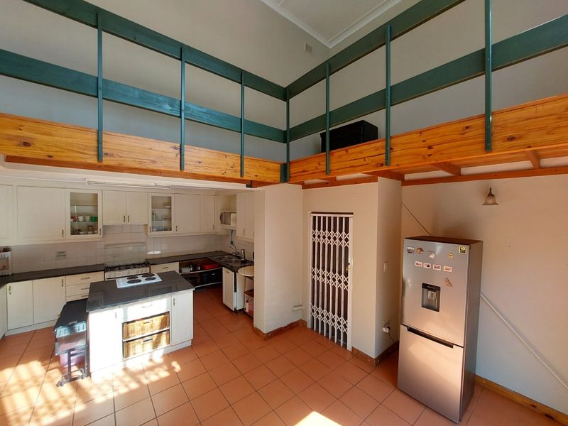 Spacious kitchen featuring a central island, ample cabinetry, and a mezzanine level overlooking the cooking area with tiled flooring throughout.