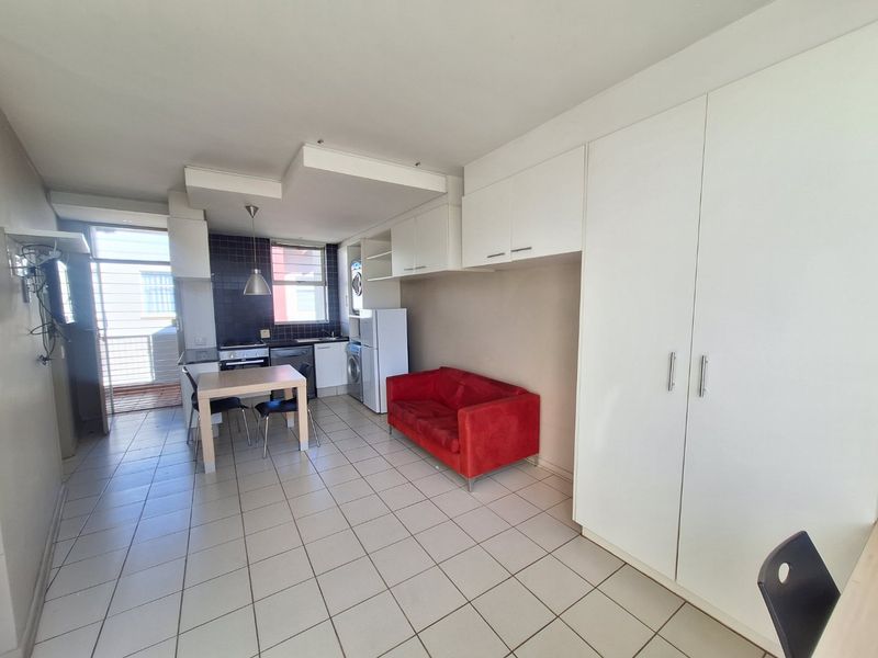 Open-plan living area featuring tiled flooring, built-in kitchen cabinetry, and integrated storage cupboards, providing a functional and versatile space.