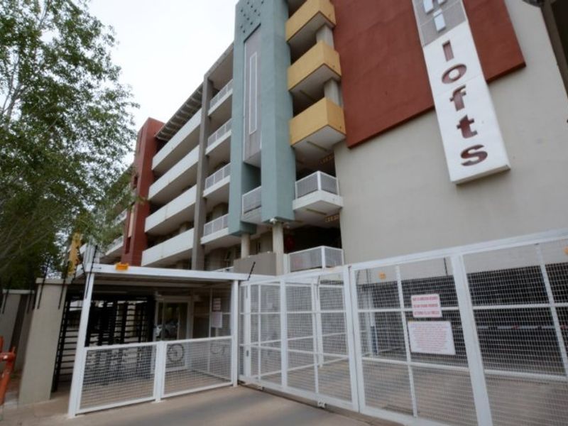 Exterior view of the apartment complex entrance featuring secure gated access, multi-level balconies, and prominent building signage.