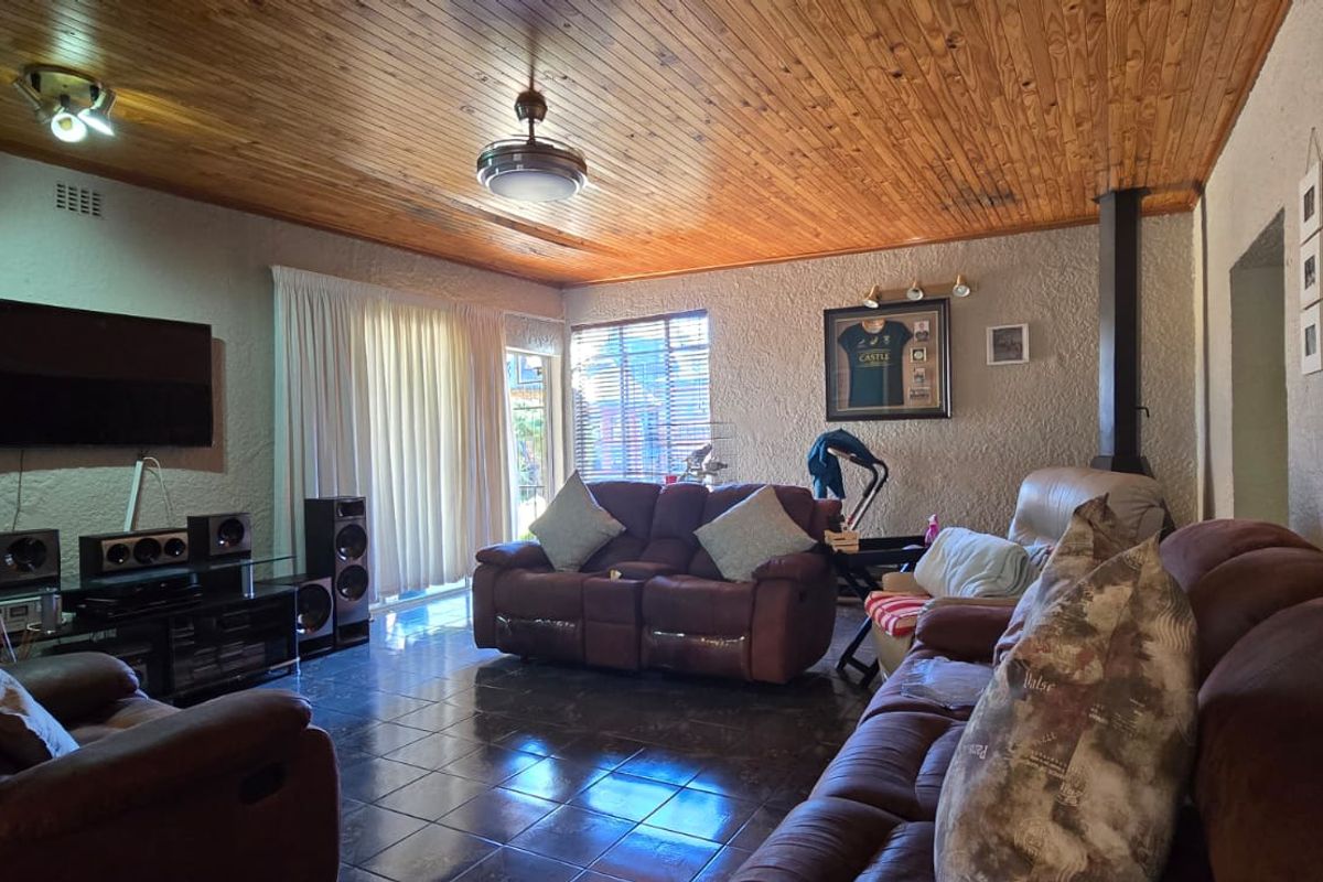 Spacious living room featuring a warm wood-paneled ceiling, tiled flooring, and a built-in fireplace, with direct access to the outdoor area via sliding doors.