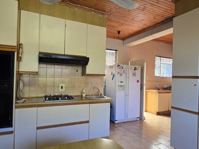 A dated kitchen featuring timber ceilings, built-in cabinetry, a gas hob, and an integrated oven, offering significant potential for modern renovation.