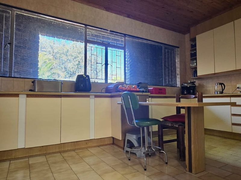 A functional kitchen featuring extensive built-in cabinetry, tiled flooring, and a timber ceiling, offering a classic layout with ample storage space.