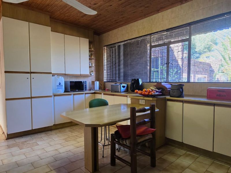 A functional kitchen featuring extensive built-in cabinetry, tiled flooring, and a timber-clad ceiling, offering ample storage and workspace with natural light.