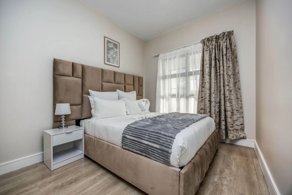 A well-maintained bedroom featuring light-toned laminate flooring and neutral wall finishes, providing a clean and comfortable living space.