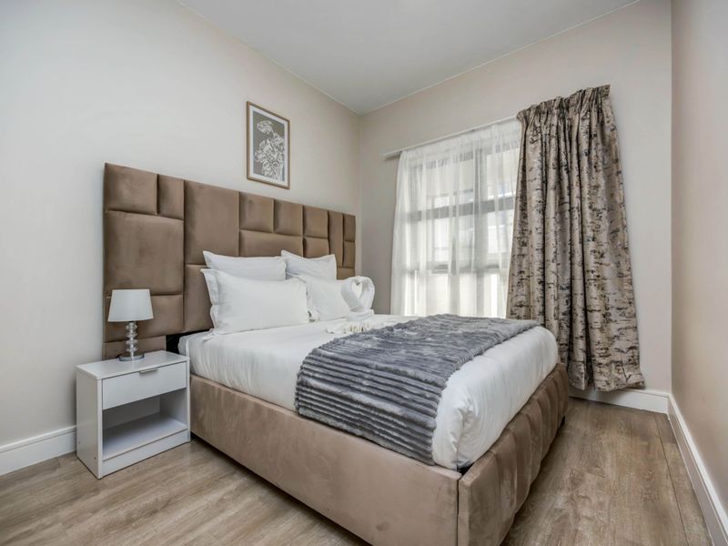 A well-maintained bedroom featuring light-toned laminate flooring and neutral wall finishes, providing a clean and comfortable living space.