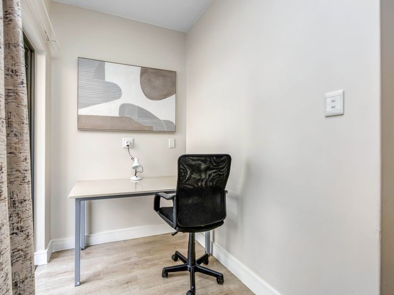 A compact home office space featuring neutral walls, laminate flooring, and integrated electrical fixtures, suitable for a dedicated workspace.