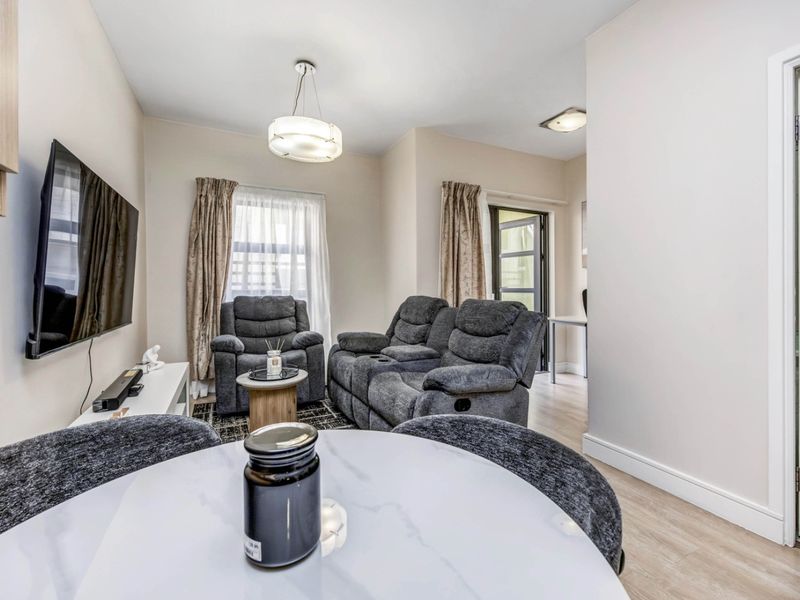An open-plan living area featuring laminate flooring, neutral walls, and modern lighting, providing a functional and well-maintained space.