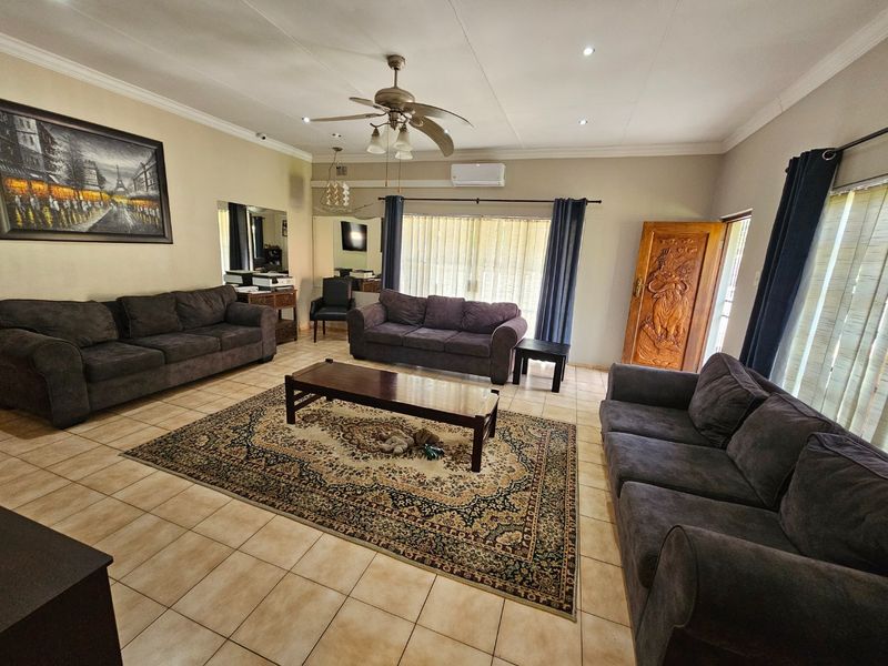 Spacious living room featuring tiled flooring, a ceiling fan, split-system air conditioning, and access to the outdoors via a sliding glass door.