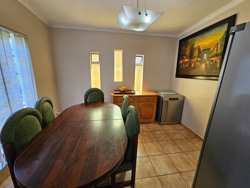 A dining room featuring tiled flooring, vertical slit windows, and a central pendant light fixture, providing a functional space for meals.
