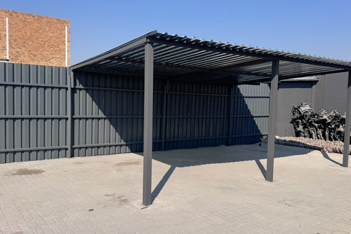A functional outdoor covered parking structure featuring a durable corrugated metal roof, steel support posts, and paved ground surface.