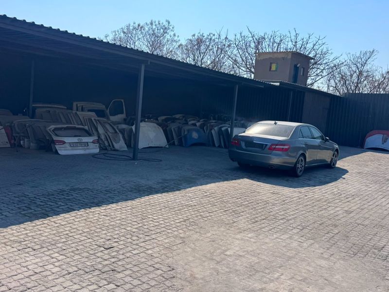 A large covered industrial parking or storage area featuring a paved driveway and metal roofing structure.