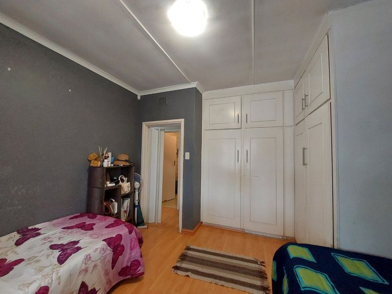 A bedroom featuring laminate flooring and extensive white built-in cupboards, providing ample storage space.