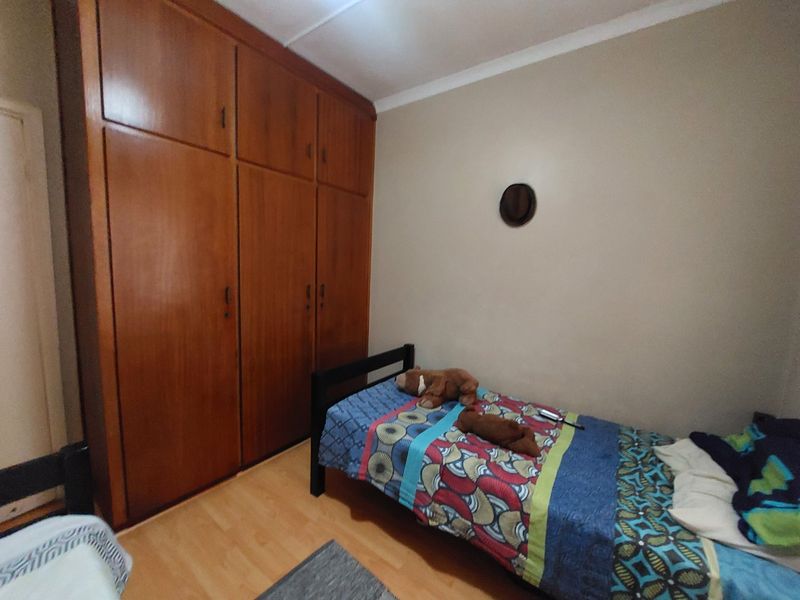 A bedroom featuring built-in wooden cupboards and laminate flooring, offering functional storage space.