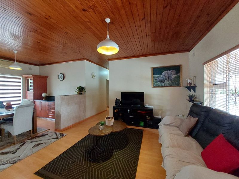Open-plan living and dining area featuring warm timber ceilings, laminate flooring, and a functional kitchen space with built-in cabinetry.