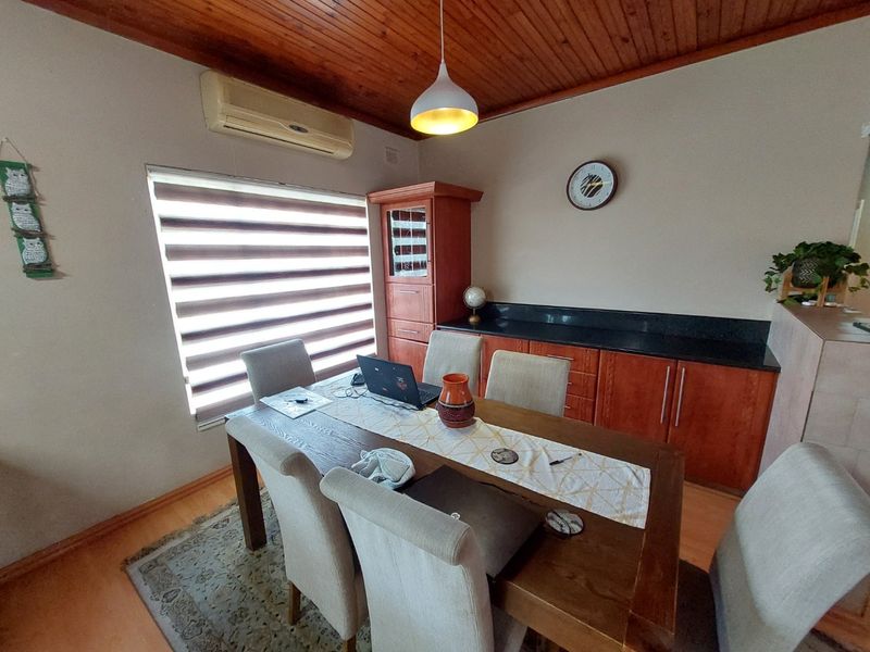 Dining room featuring a timber ceiling, laminate flooring, built-in cabinetry with granite countertops, and a wall-mounted air conditioning unit.