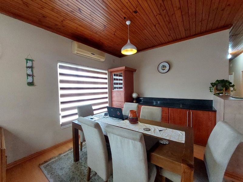 Dining room featuring a warm timber ceiling, built-in cabinetry with granite countertops, and a wall-mounted air conditioning unit.