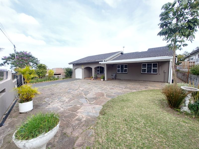 Front exterior view of a single-story house featuring a stone-paved driveway, tiled roof, and a covered entrance area.