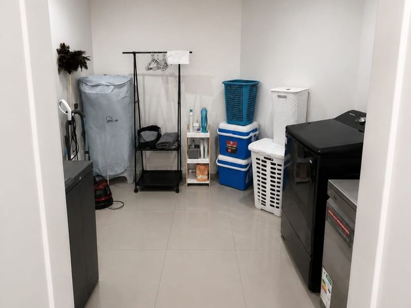 A functional laundry room featuring neutral tiled flooring and recessed ceiling lighting, providing a clean and practical space for household utility tasks.