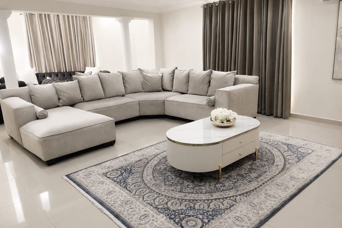 A spacious, well-maintained living room featuring neutral tiled flooring, recessed lighting, and structural columns, creating an open and inviting atmosphere.