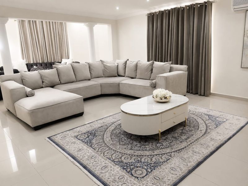 A spacious, well-maintained living room featuring neutral tiled flooring, recessed lighting, and structural columns, creating an open and inviting atmosphere.