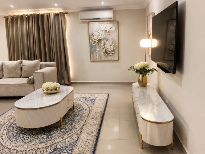 A well-maintained living room featuring tiled flooring, recessed downlighting, and a wall-mounted split-system air conditioning unit.