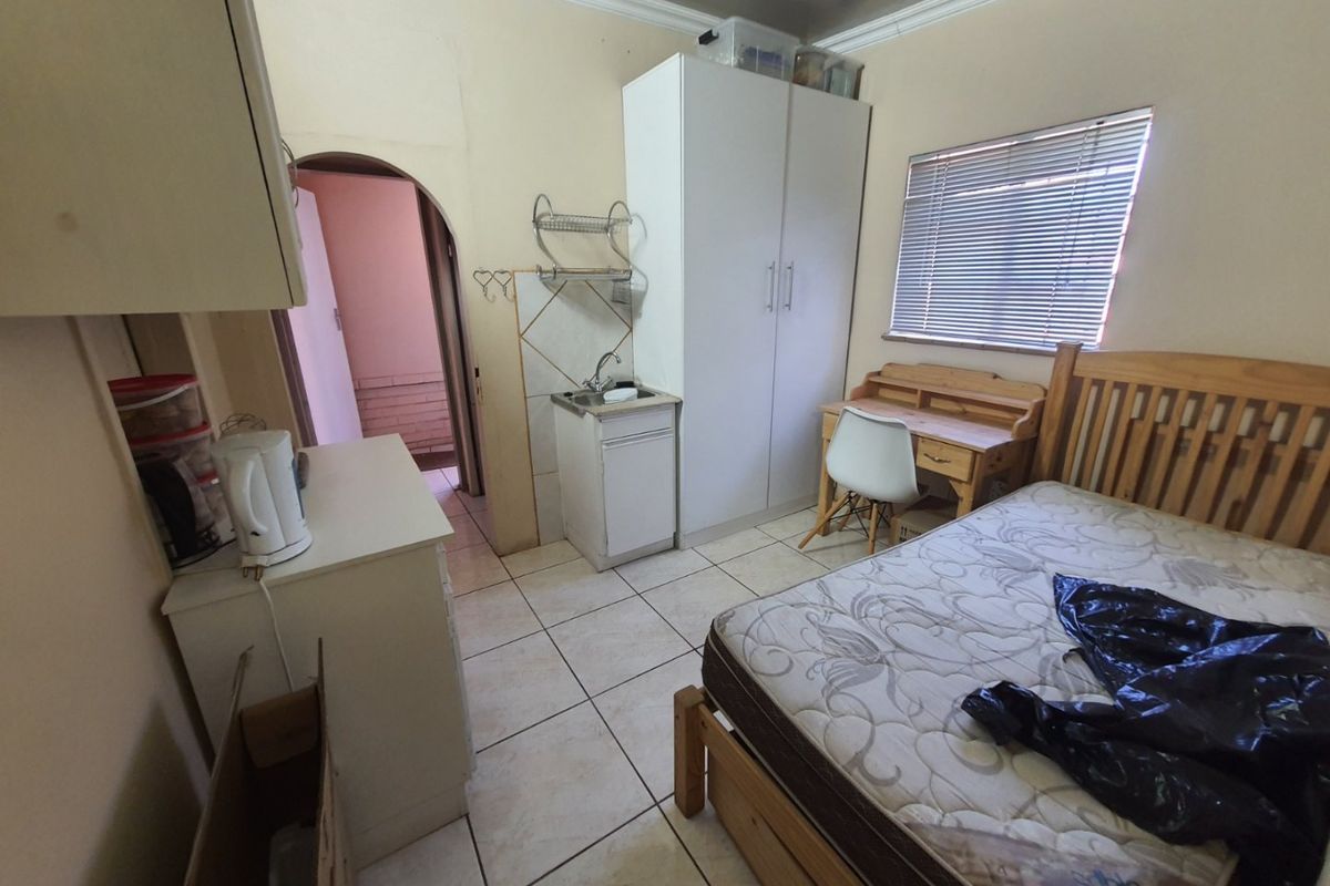 Bedroom featuring tiled flooring, a built-in cupboard, and a small kitchenette sink area, with an archway leading to an adjacent space.