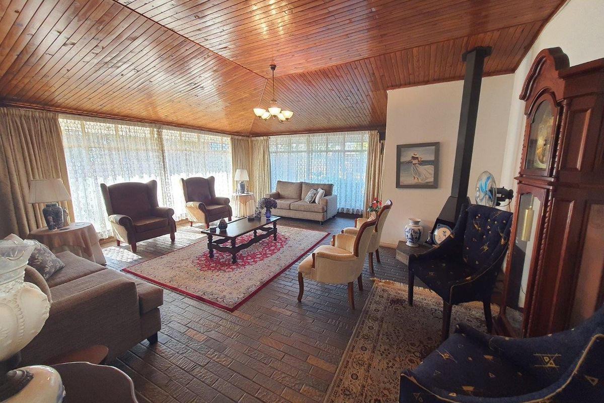 Spacious living room featuring a vaulted wood-paneled ceiling, brick flooring, and a freestanding fireplace, offering a warm and traditional aesthetic.
