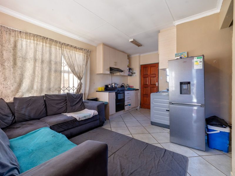 Open-plan living and kitchen area featuring tiled flooring, built-in cabinetry, and direct access to an exterior door.