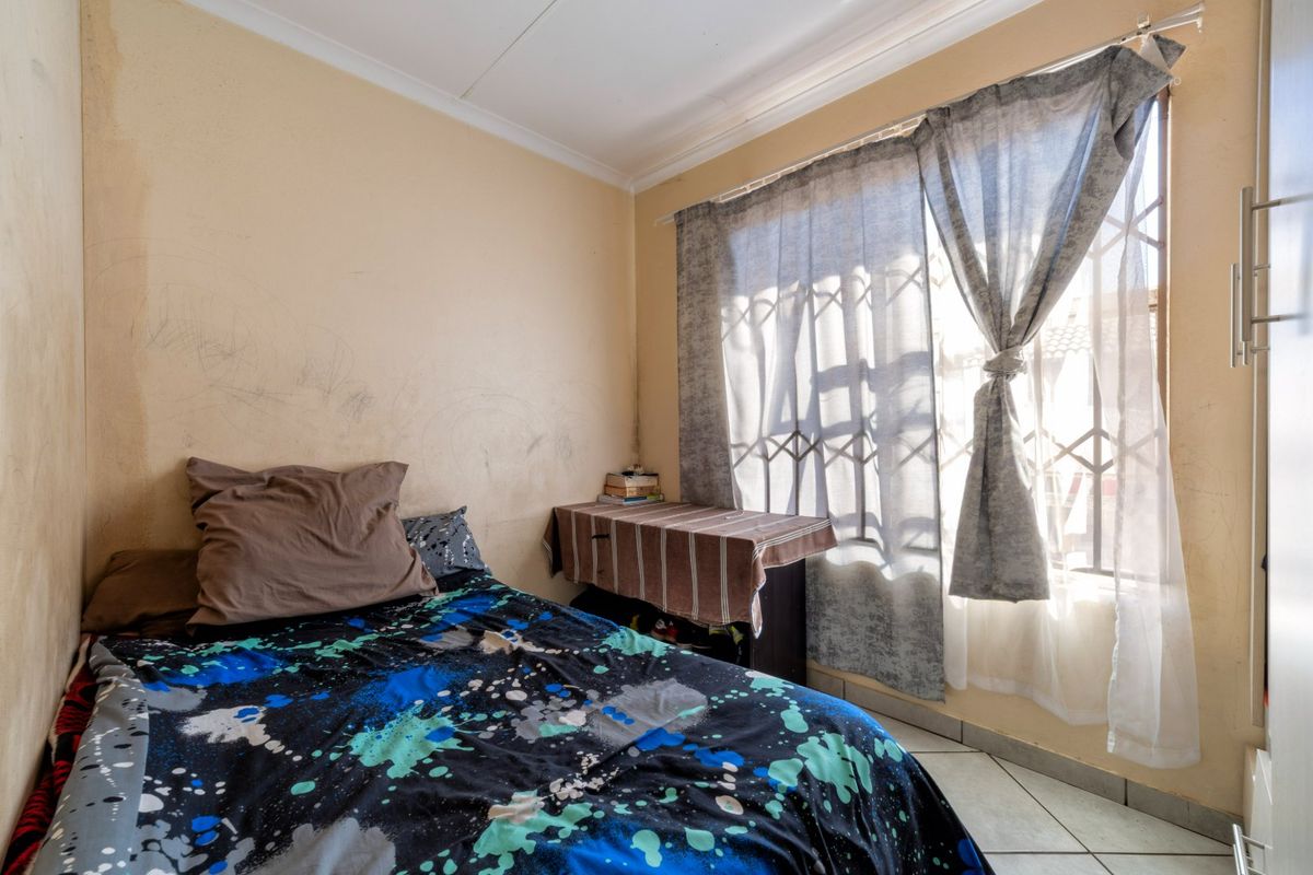A bedroom featuring tiled flooring and a security gate on the window, requiring cosmetic attention to the wall surfaces.