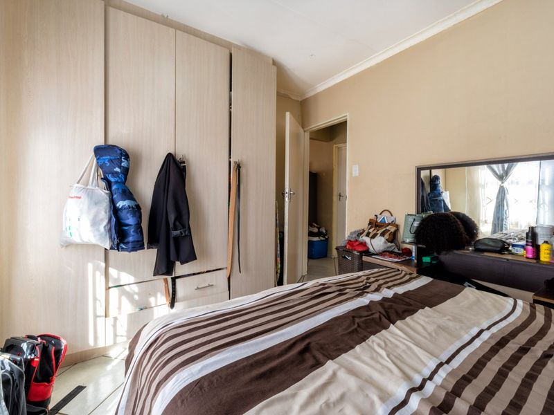 A bedroom featuring built-in wardrobes and tiled flooring, offering a functional space with neutral wall tones.
