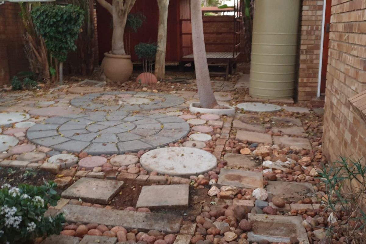 A rear courtyard area featuring brick walling, paved sections, and a water tank, requiring maintenance and landscaping improvements to enhance the outdoor space.