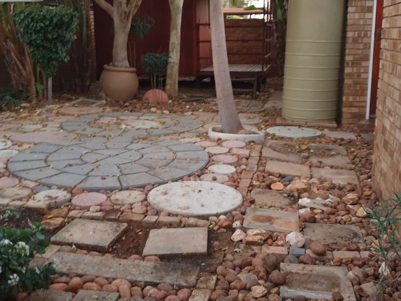 A rear courtyard area featuring brick walling, paved sections, and a water tank, requiring maintenance and landscaping improvements to enhance the outdoor space.
