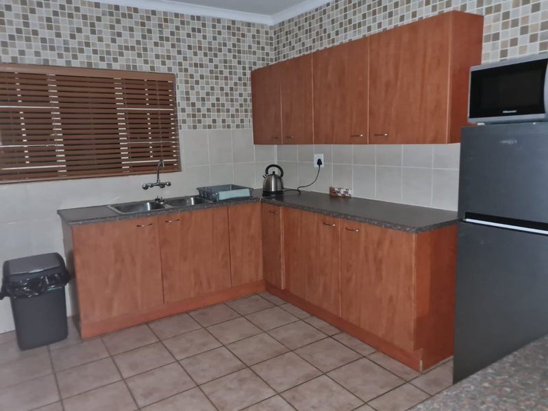 A functional kitchen featuring laminate cabinetry, mosaic tile backsplash, double basin sink, and ceramic floor tiles.