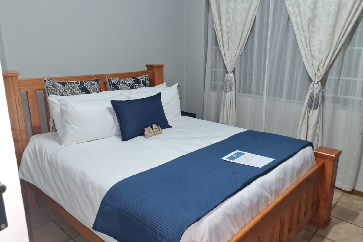 A well-maintained bedroom featuring tiled flooring and large windows with installed curtain tracks, providing a functional and comfortable living space.