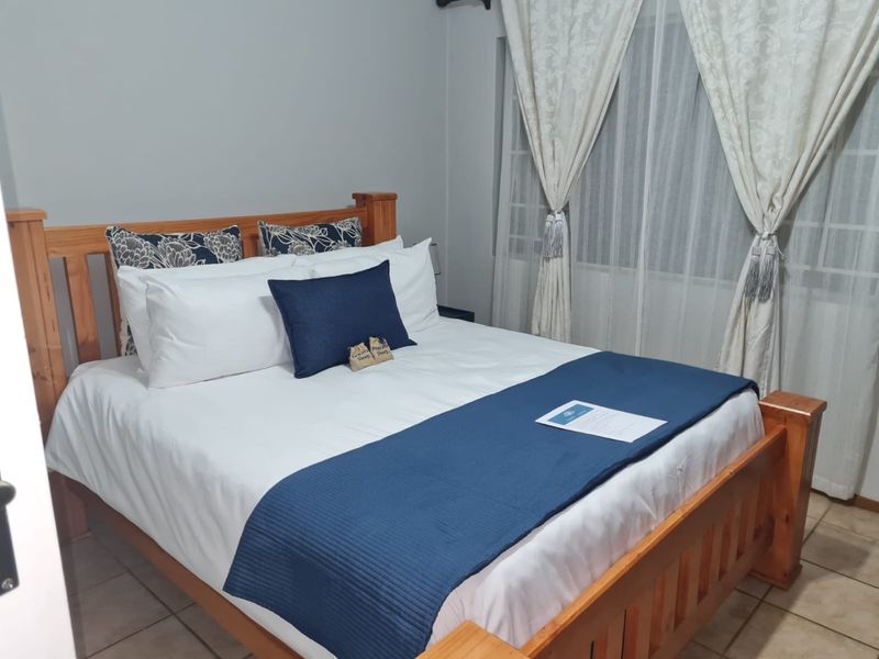 A well-maintained bedroom featuring tiled flooring and large windows with installed curtain tracks, providing a functional and comfortable living space.