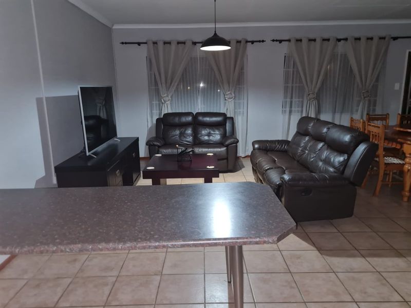 Open plan living and dining area featuring tiled flooring, a breakfast bar counter, and neutral wall tones.