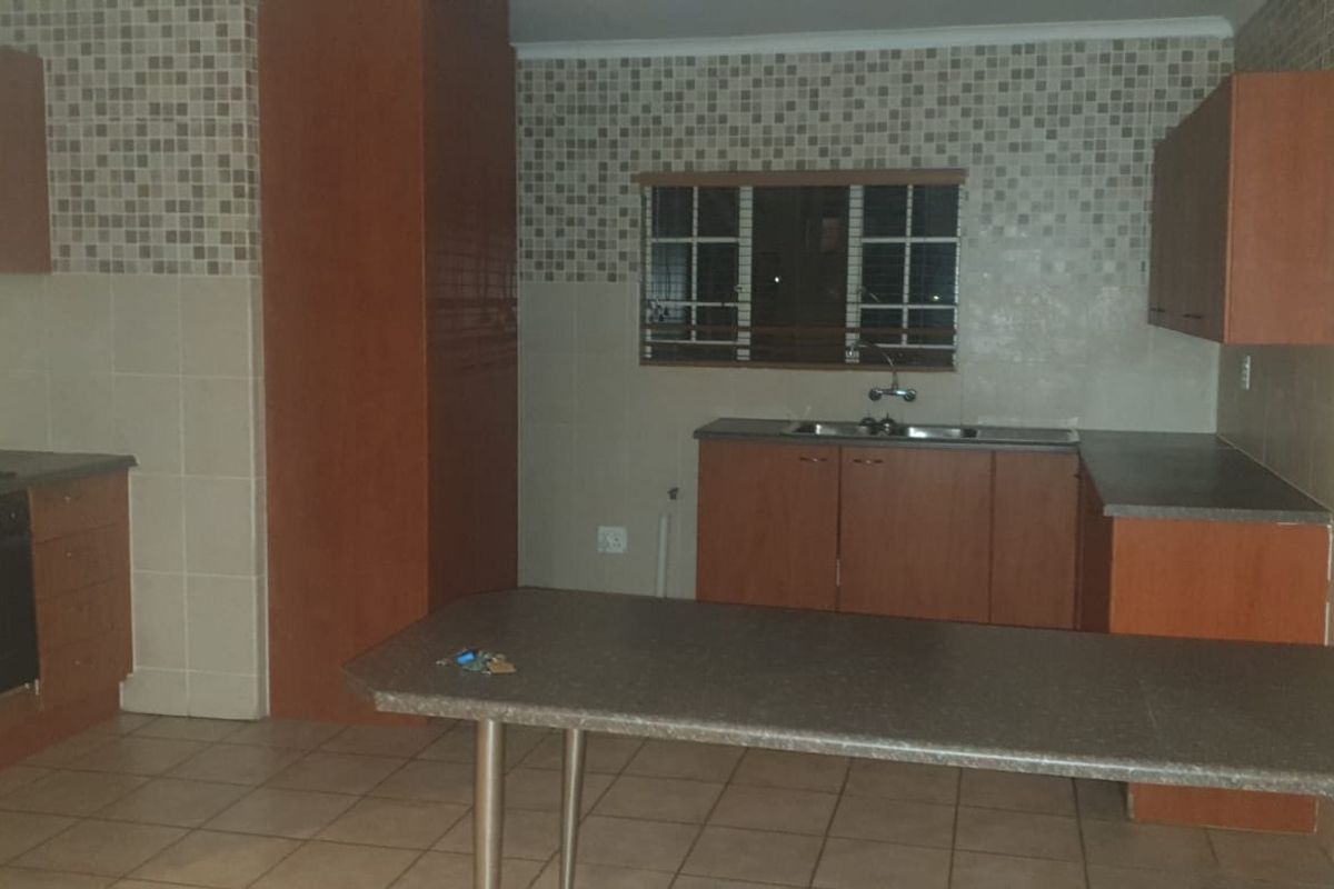 A functional kitchen featuring built-in wooden cabinetry, laminate countertops, a breakfast bar, and a tiled backsplash with an integrated oven and hob.