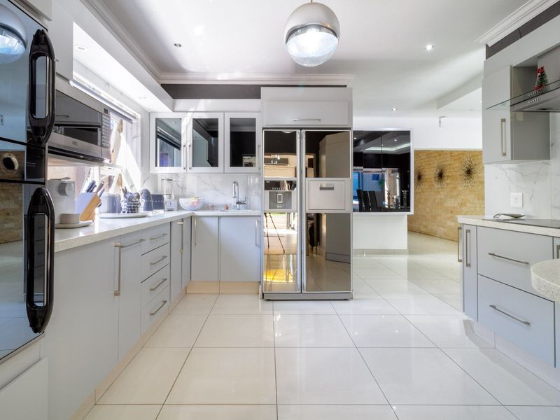 Modern kitchen featuring sleek cabinetry, stone countertops, integrated appliances, and polished tile flooring, offering a clean and contemporary aesthetic.