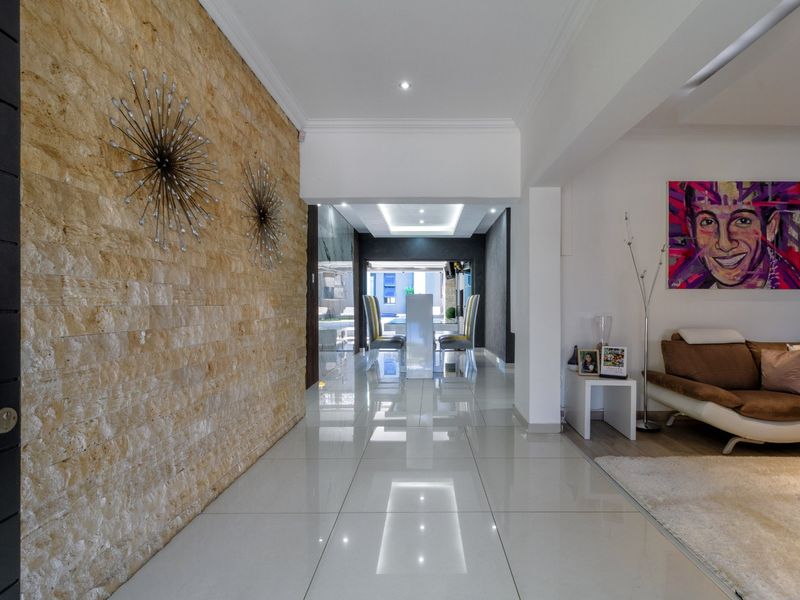 Welcoming entrance hall featuring a striking natural stone feature wall, polished porcelain floor tiles, and modern recessed ceiling lighting leading into the living area.