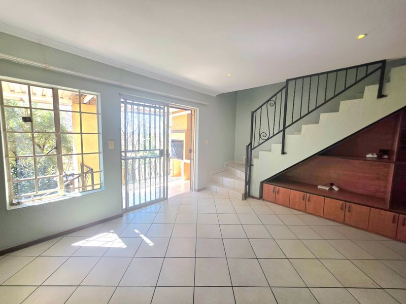 Spacious living area featuring tiled floors, a staircase with built-in under-stair storage, and direct access to an outdoor patio area.