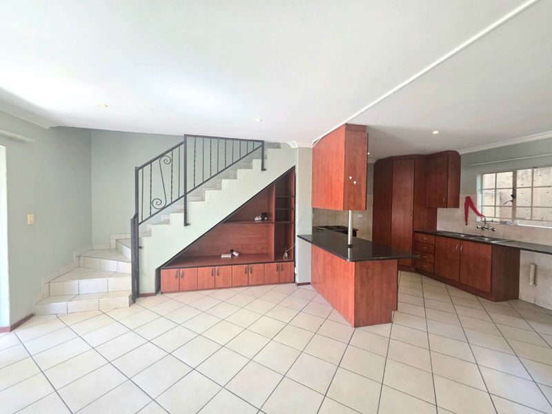 Open-plan living area featuring a kitchen with built-in cabinetry, a breakfast island, and a staircase with integrated under-stair storage.