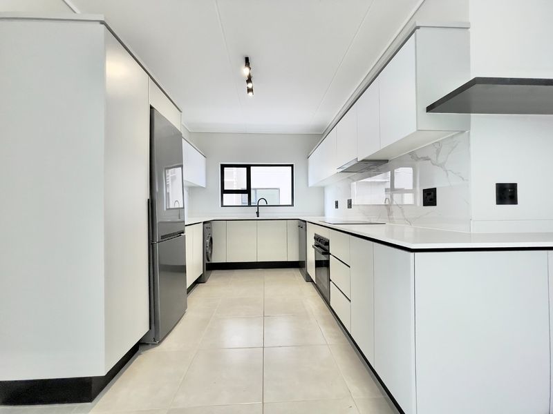 Modern, minimalist kitchen featuring sleek white cabinetry, stone countertops, marble-look splashback, and integrated appliances in a clean, bright, and well-maintained space.