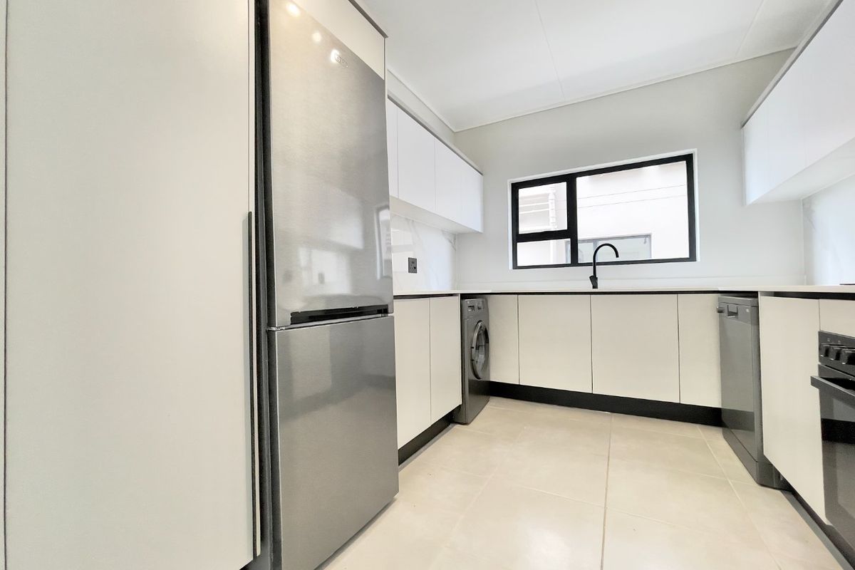 Modern kitchen featuring sleek white cabinetry, stone countertops, integrated appliances, and high-quality tiled flooring with a clean, contemporary aesthetic.