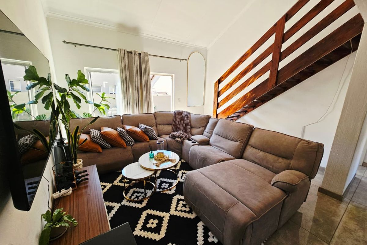 A comfortable living room featuring tiled flooring and a prominent wooden staircase, creating an open and inviting atmosphere.