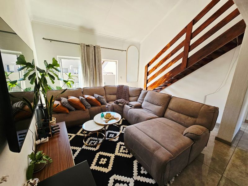 A comfortable living room featuring tiled flooring and a prominent wooden staircase, creating an open and inviting atmosphere.