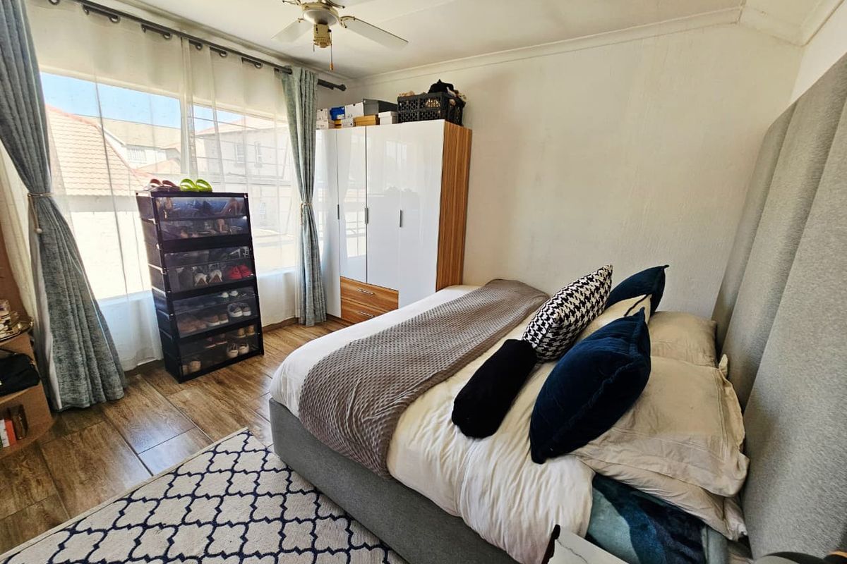 A well-lit bedroom featuring tiled flooring, a ceiling fan, and a large window providing natural light.